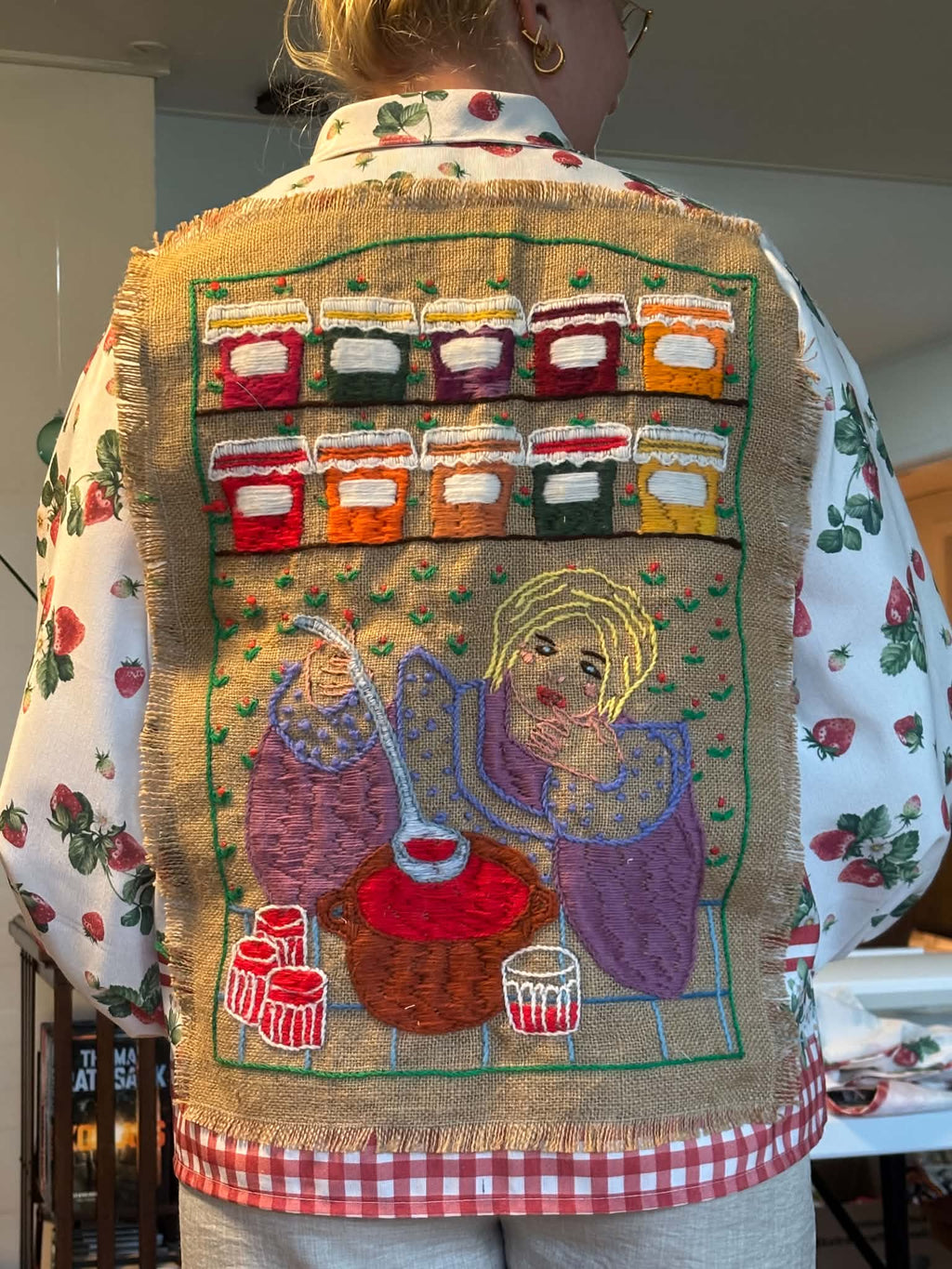 Close-up of embroidered preserve-making scene on strawberry shirt